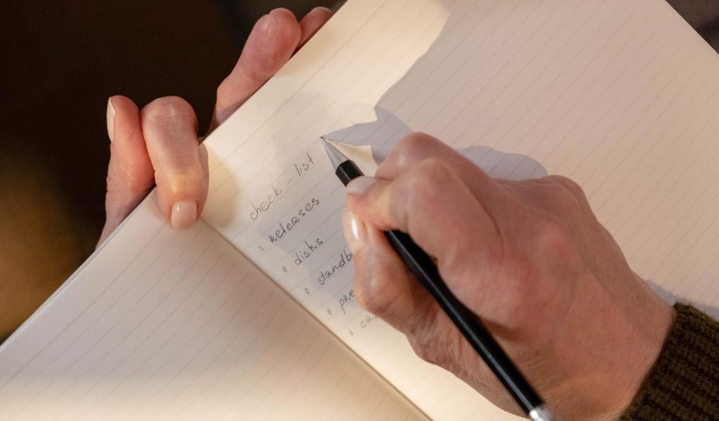 Person writing a check list in a journal or notebook